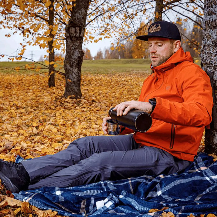 - Vīrietis valkā FHM Explorer lietus uzvalku, sēžot uz sega rudens mežā.
- Terrakota krāsas ūdensizturīgs jaka ar pielāgojamu kapuci un aprocēm.
- Vīrietis gatavo dzērienu izmantojot termosu, attēlā redzami koki un rudens lapas.
- Zili bikses ar elastīgu jostu un ūdensnecaurlaidīgiem rāvējslēdzējiem.
- Lietus uzvalks ideāli piemērots āra aktivitātēm, piemēram, pārgājieniem un ceļojumiem.
- FHM,