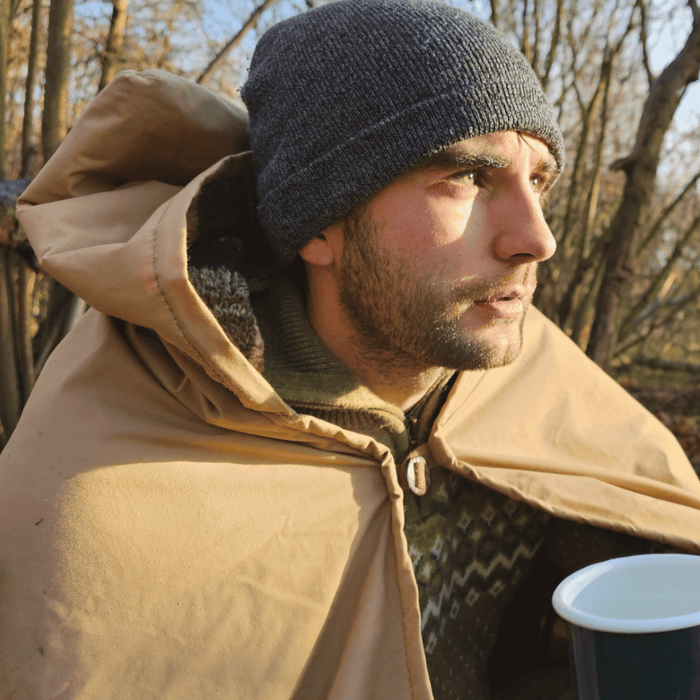 Vīrietis mežā izmanto FRONTIER Blanket™ kā pončo