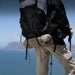 Person hiking with a backpack and walking sticks on a mountain with ocean view