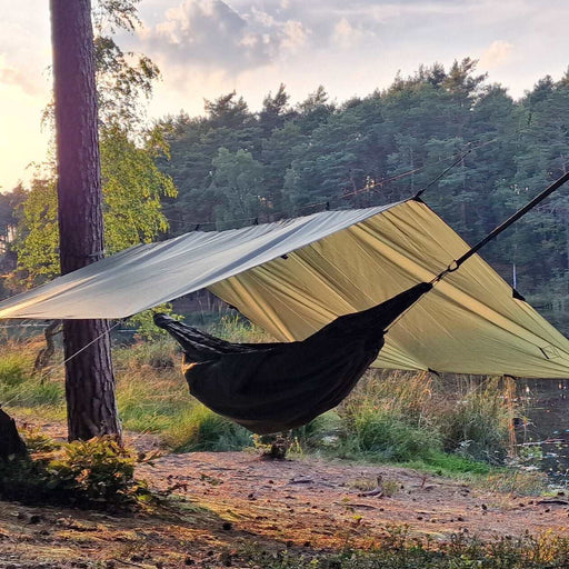 - Zaļš 3x3 metru tarps, kas nojaušams starp kokiem meža skata fondā.
- Ūdensizturīgs tarps uzstādīts virs šūpuļtīkla.
- Tarps aprīkots ar 19 cilpām, iekļautām alumīnija mietiņām, puišiem un elastīgajām PRUSIK-PRO cilpām.
- Bushmen,