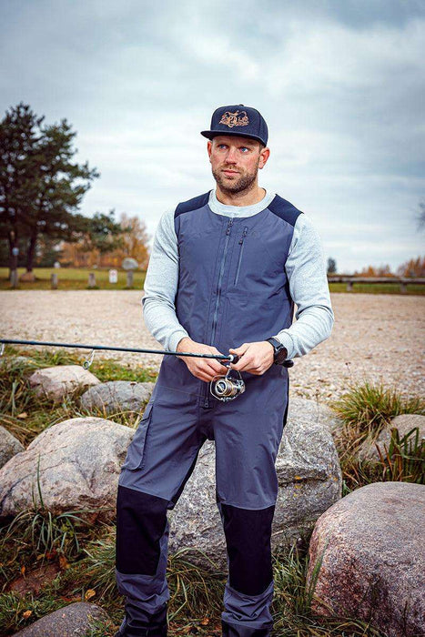 - Vīrietis, velkot FHM Guard Competition Waterproof Fishing Pants 20000mm Grey, 
- Zvejošanas bikses ar trīs slāņu laminētu konstrukciju,
- Ūdensdrošs bikses ar pārseguma šuvēm,
- Elastīgi pleci un regulējamas Velcro apakšējās aproces,
- Vīrietis, tur zivs ēsmu vēsā, akmeņainā vidē,
- Stāvot laukā, gatavs laivu zvejai vai ārā aktivitātēm.
- FHM