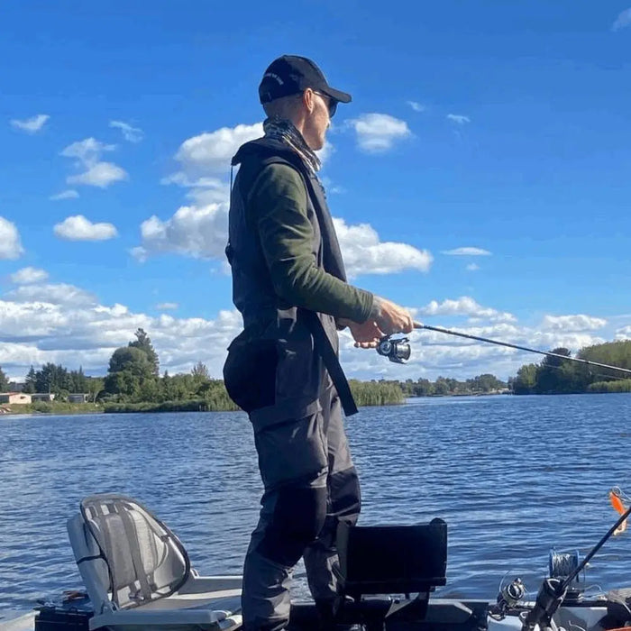 - Makšķerēšanas Kombinezons
- Vīrietis makšķerē uz laivas, valkājot pelēkas FHM Guard Competition Waterproof Fishing Pants. 
- Skats uz ezeru ar mākoņainām debesīm fonā. 
