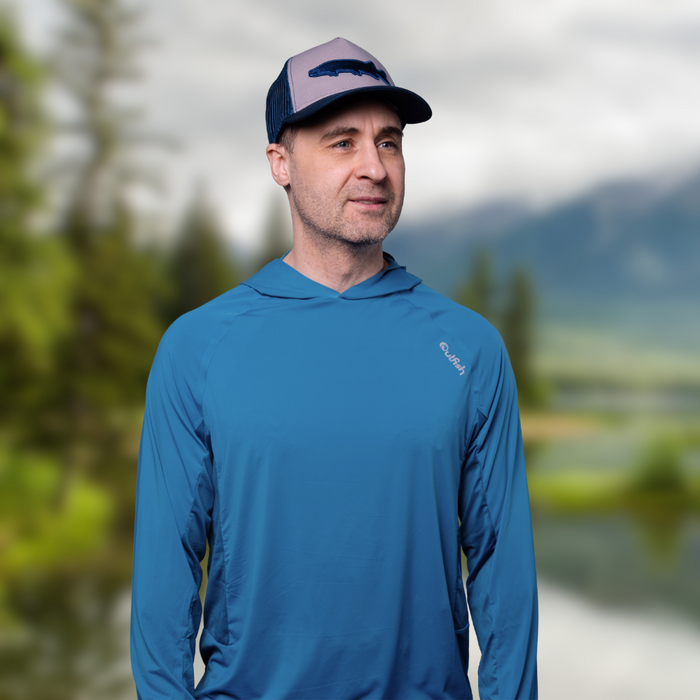 - Cilvēks, kas nēsē tērauda zilu "Outfish Insect Shield UV Protection Hoodie UPF50+" kapuci
- Kapuce nodrošina aizsardzību pret UV stariem un odiem
- Ideāli piemērots āra aktivitātēm, piemēram, pārgājieniem, kempingiem un makšķerēšanai
- Elpojošs un ātri žūstošs audums nodrošina ērtumu un svaigumu
- Attēls uzņemts dabā, ar zaļu fonu
- Outfish